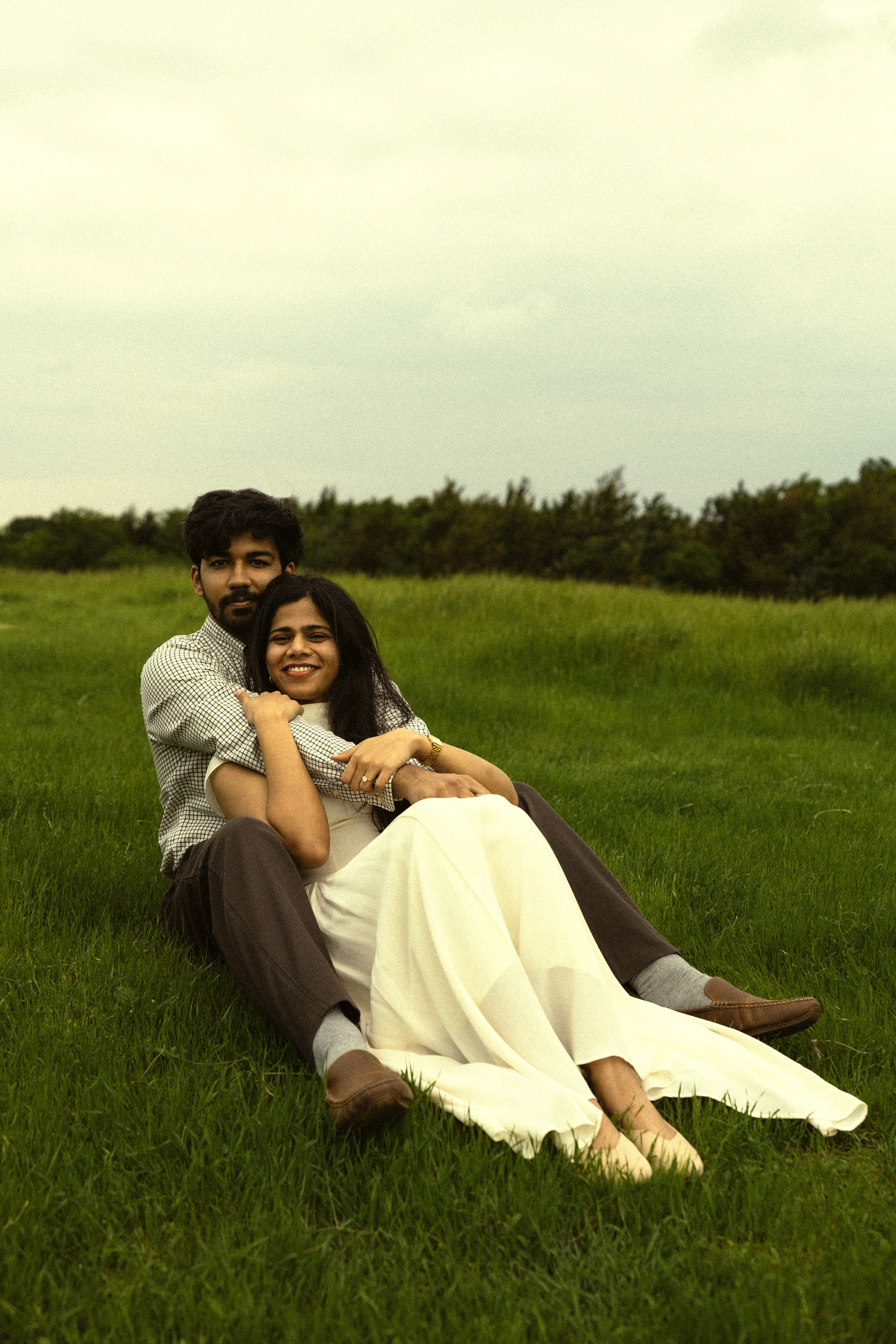 Durga and Akhil sitting together in a grassy field